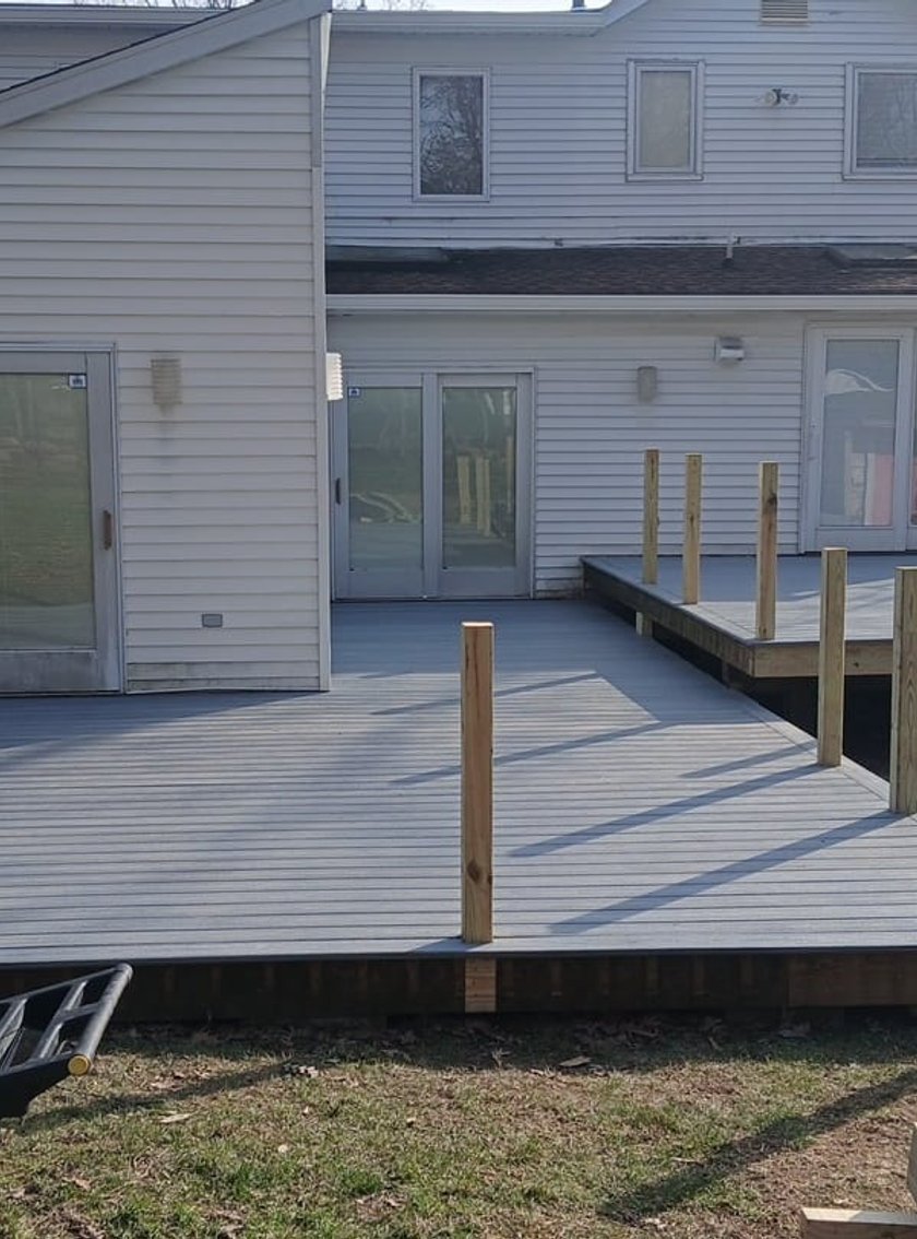Backyard composite deck mid-construction with vertical wood railings