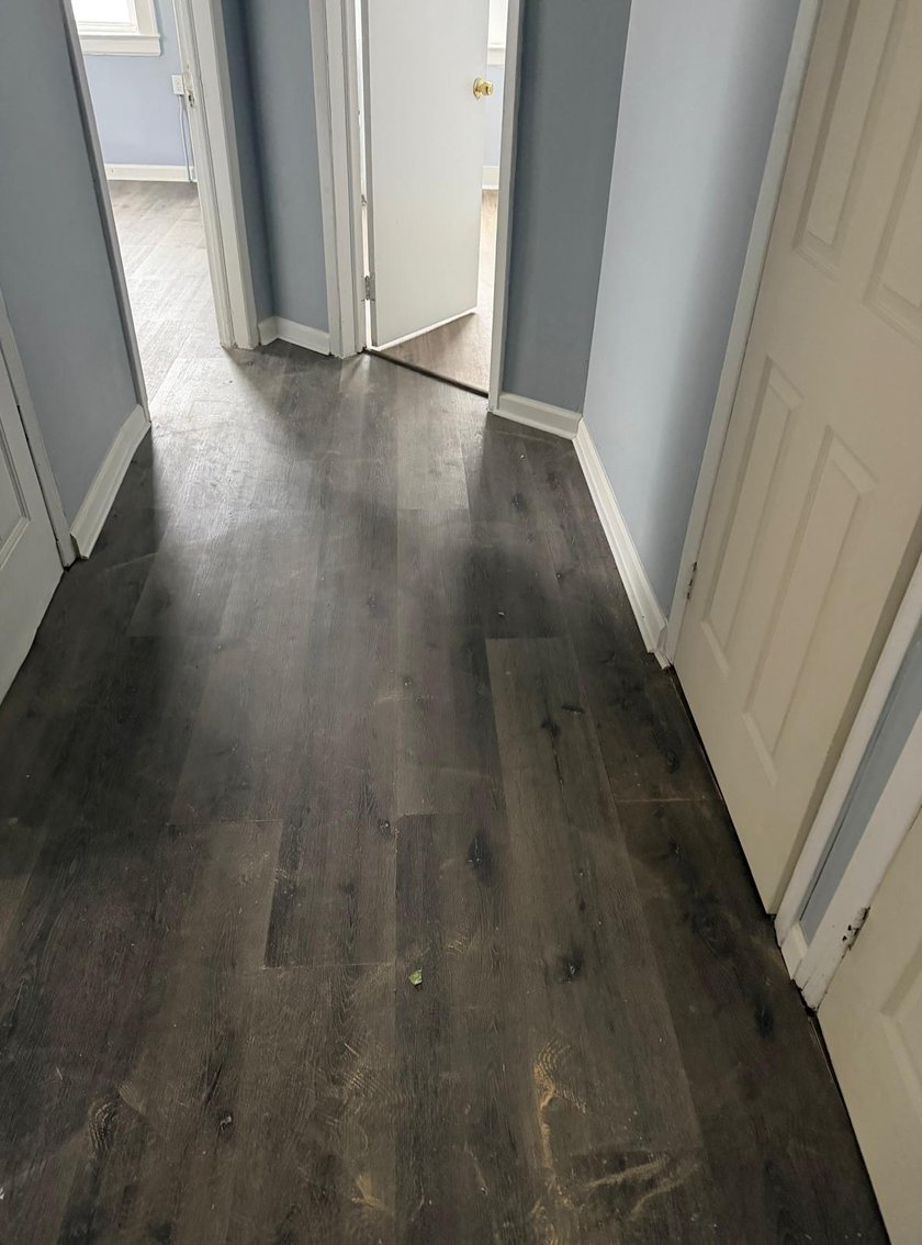 Hallway between rooms with dusty blue walls and dark luxury vinyl plank flooring