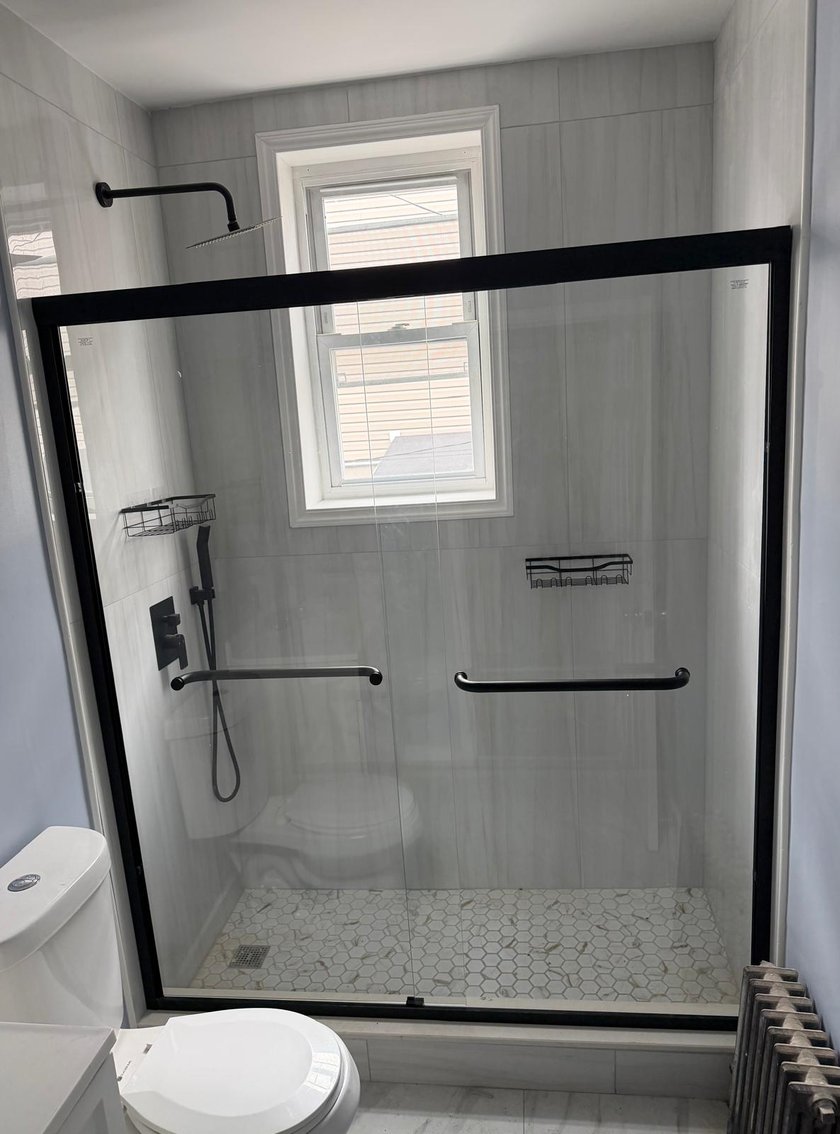 Walk-in shower with black-framed glass and hexagon marble floor
