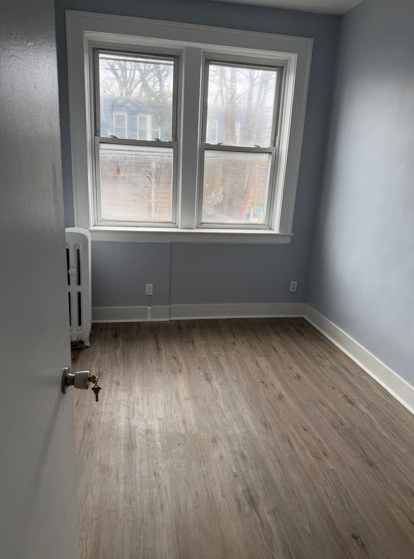 Bedroom with dusty blue walls, a double window with original radiator, and new gray wood-look vinyl plank flooring
